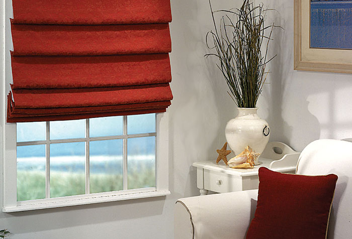 Римская штора красного цвета и декоративная подушка в тон